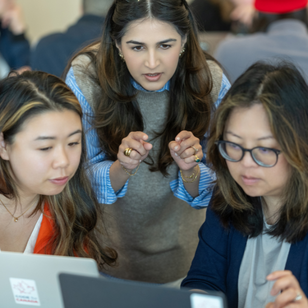 Three people gathered looking at a computer screen